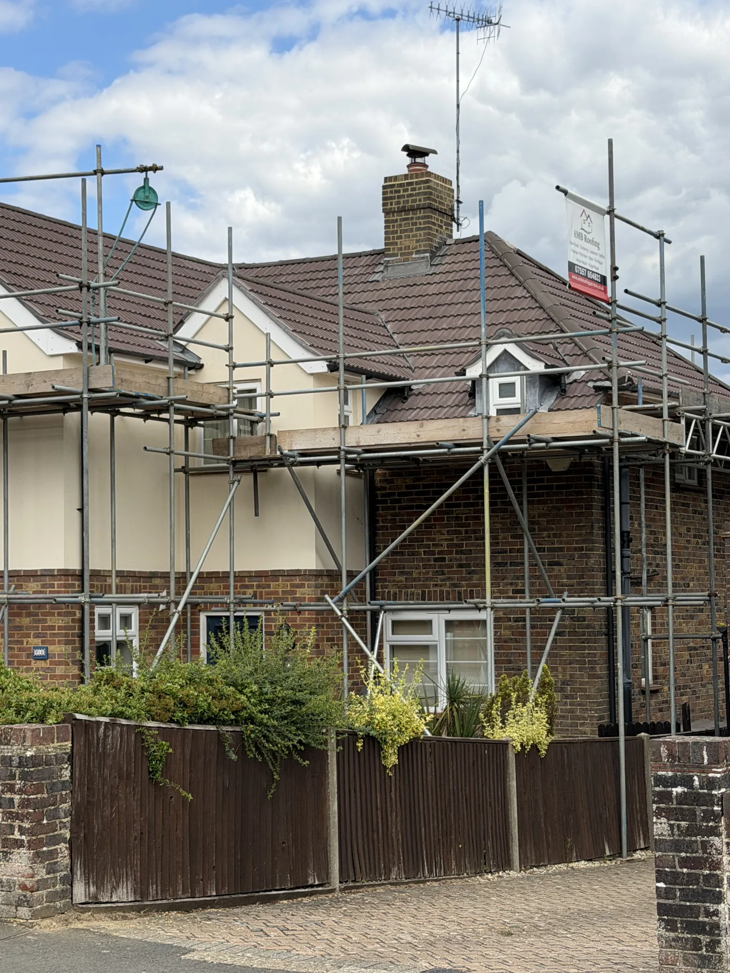 Completed roof renewal with scaffolding and AMB Roofing banner